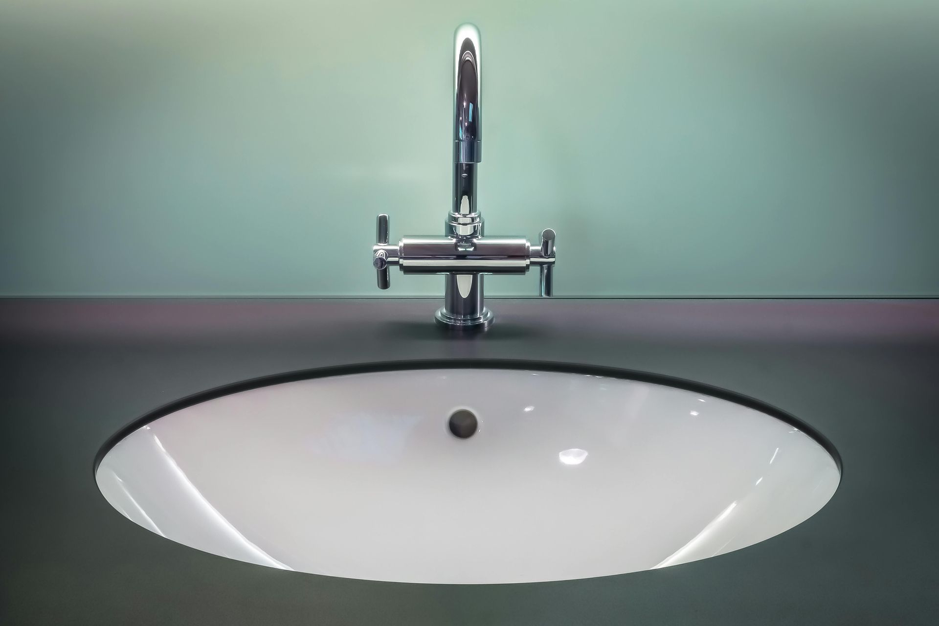 Modern white sink with chrome faucet against a green wall