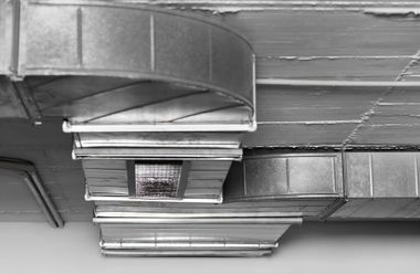 Ceiling ductwork and vents in an industrial interior, shown in grayscale.