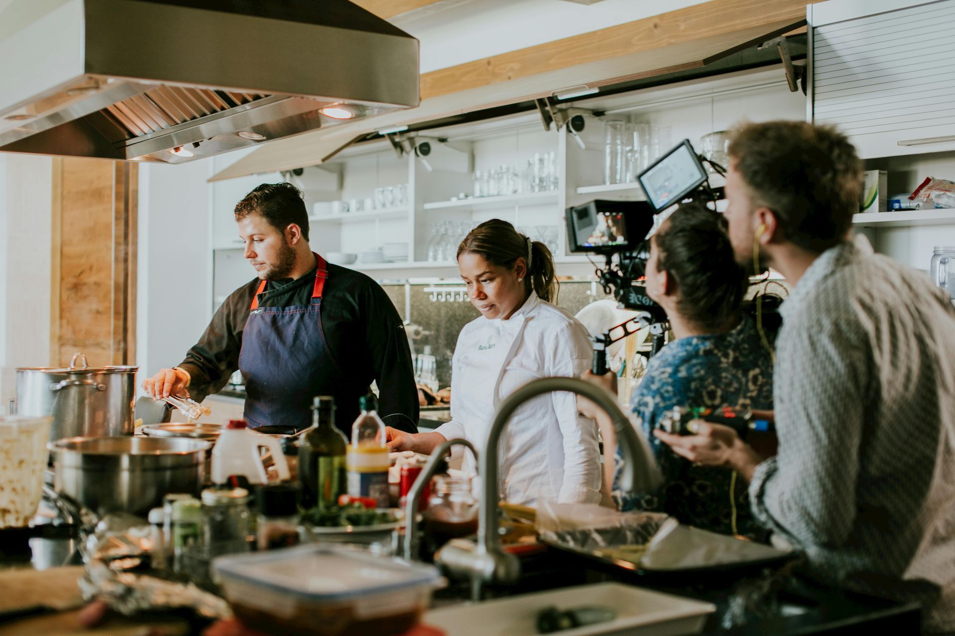 Chef demonstrating food prep to a small group in a bright kitchen classroom