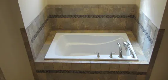 A bathtub is sitting in a corner of a bathroom.