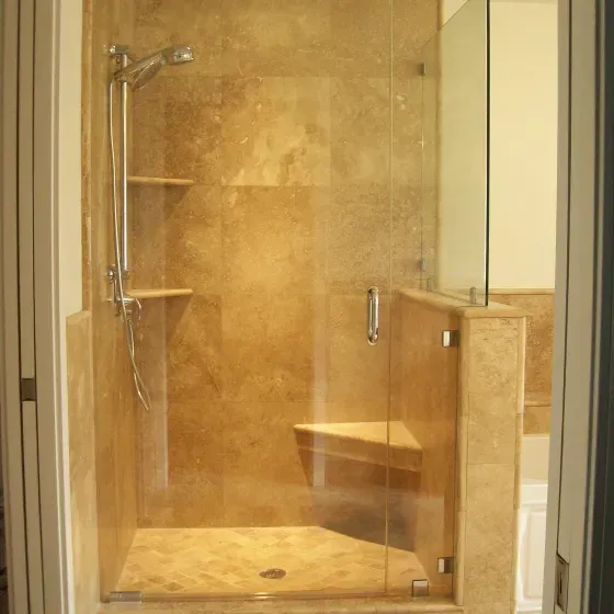 A bathroom with a walk in shower with a glass door