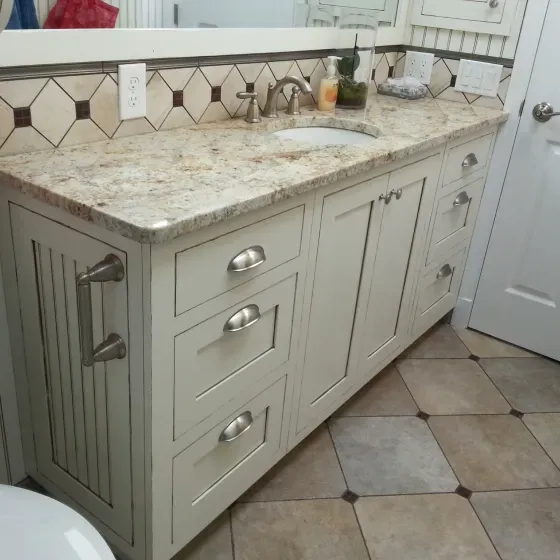 A bathroom with white cabinets a sink and a toilet