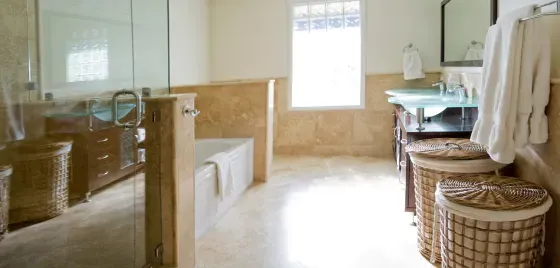 A bathroom with two sinks , a tub , a mirror and wicker baskets.