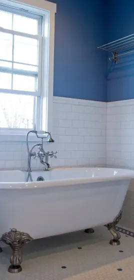 There is a bathtub in the bathroom with blue walls.