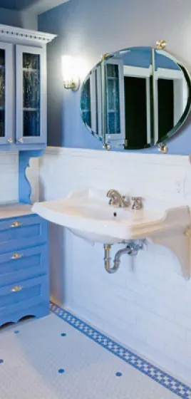 A bathroom with a sink , mirror and blue cabinets