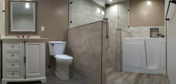 A bathroom with a toilet , sink , mirror and walk in shower.