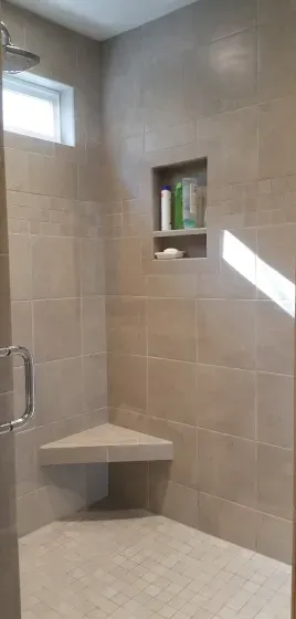 A shower with a corner bench and a window.