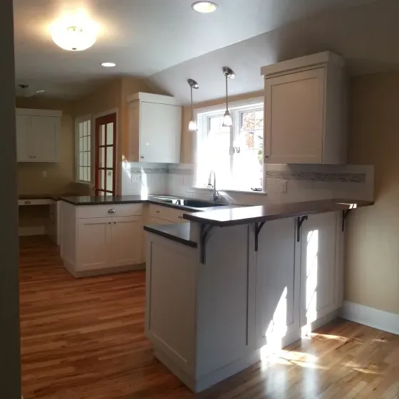 A kitchen with hardwood floors and white cabinets