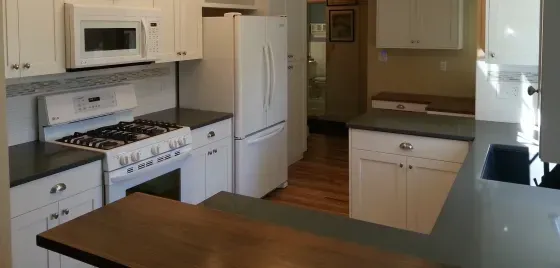 A kitchen with a stove , refrigerator , microwave and sink