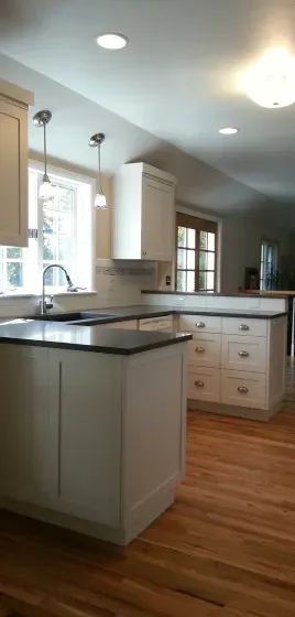 A kitchen with white cabinets and black counter tops