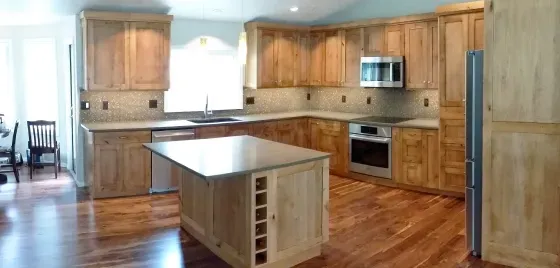 A kitchen with wooden cabinets , granite counter tops , stainless steel appliances and a large island.