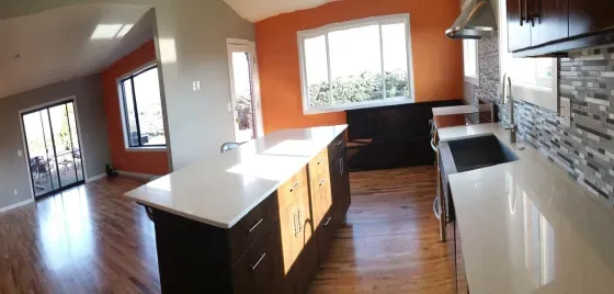 A kitchen with orange walls and white counter tops