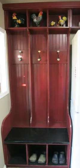 A wooden locker with chickens on the shelves and a bench.