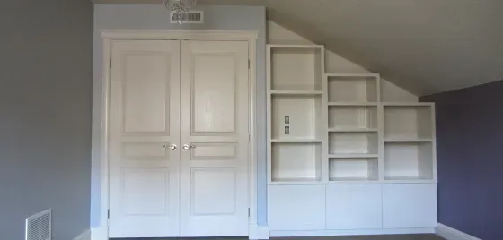 A room with a slanted ceiling and white shelves