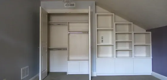 A closet with a slanted ceiling and shelves in a room.