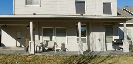 A white house with a porch and chairs in front of it.