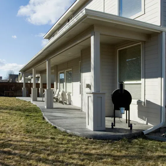 A white house with a porch and a grill