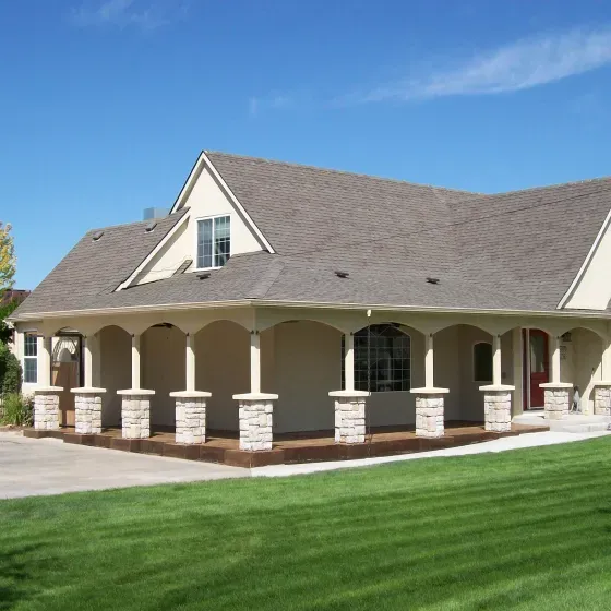A house with a large porch and a blue sky in the background