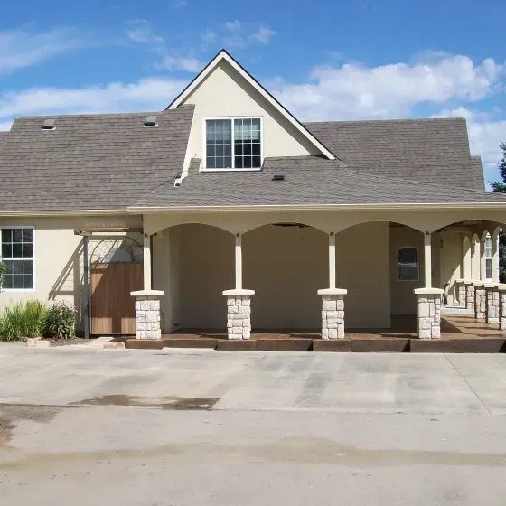 A white house with a gray roof and a porch