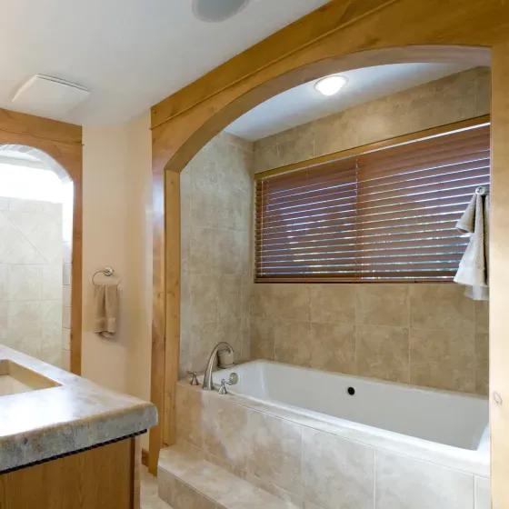 A bathroom with a tub and a window with blinds