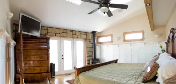 A bedroom with a large bed and a ceiling fan