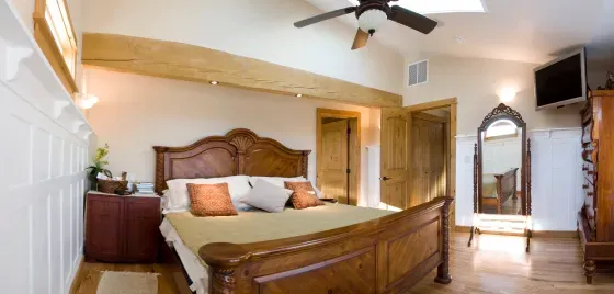 A bedroom with a king size bed and a ceiling fan