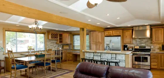 A living room filled with furniture and a kitchen with a ceiling fan.