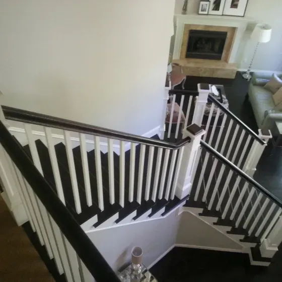 A black and white staircase with a fireplace in the background
