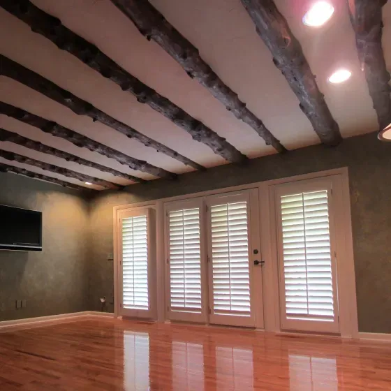 An empty living room with shutters on the doors