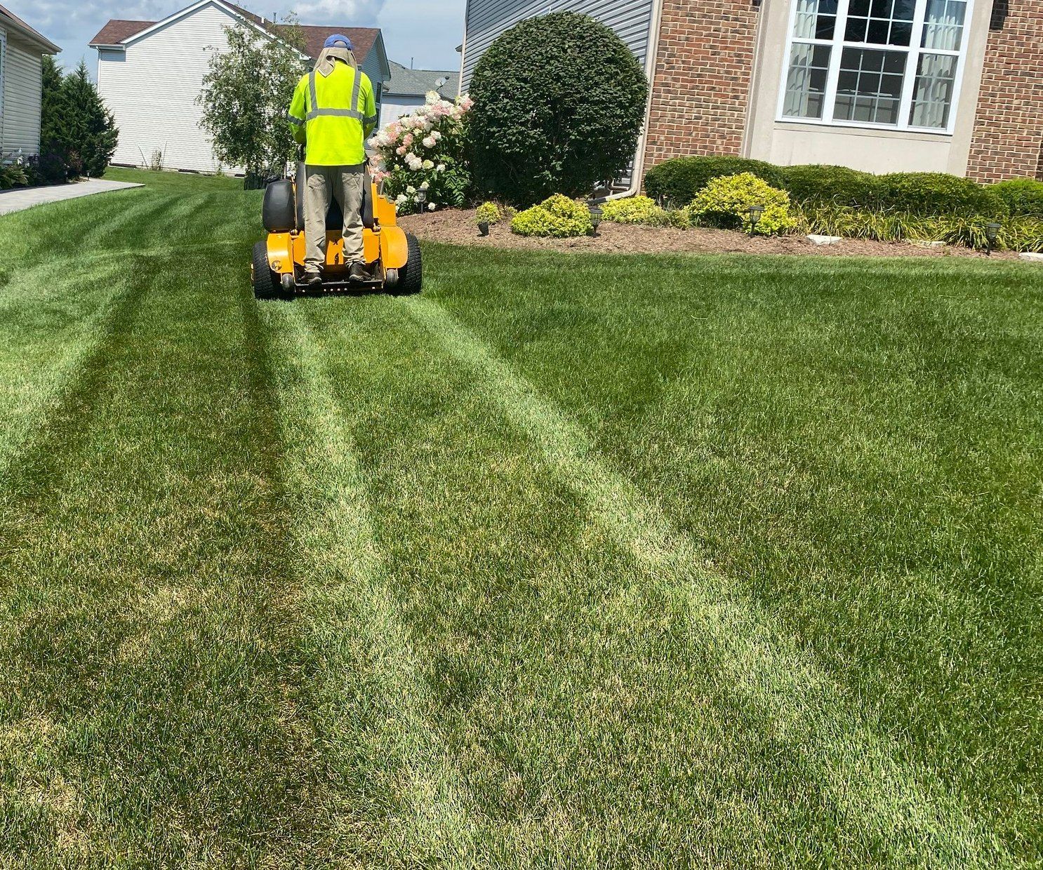 A man is riding a lawn mower on a lush green lawn.
