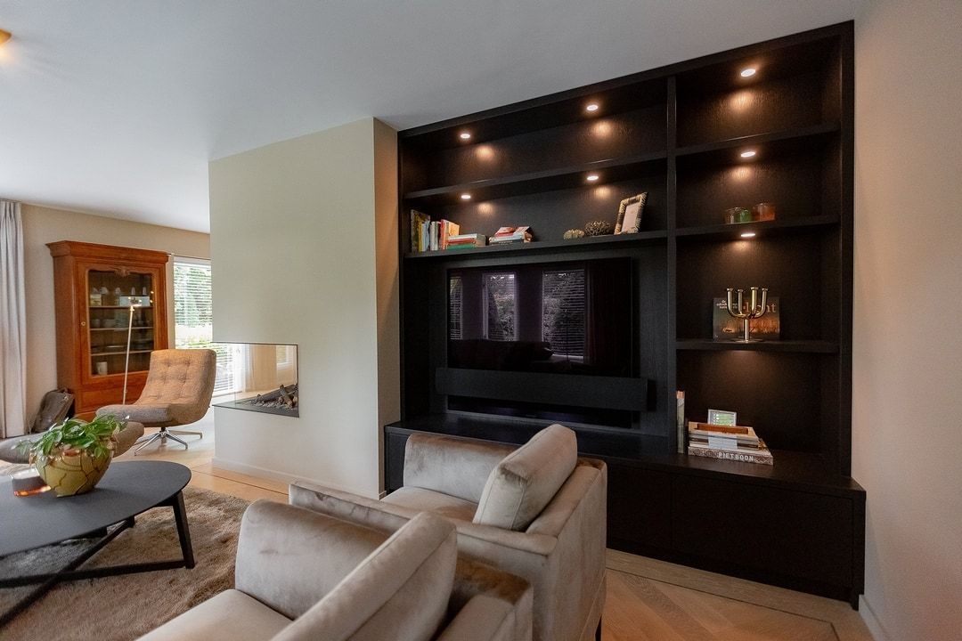 Een woonkamer met een bank, stoelen, salontafel en televisie.