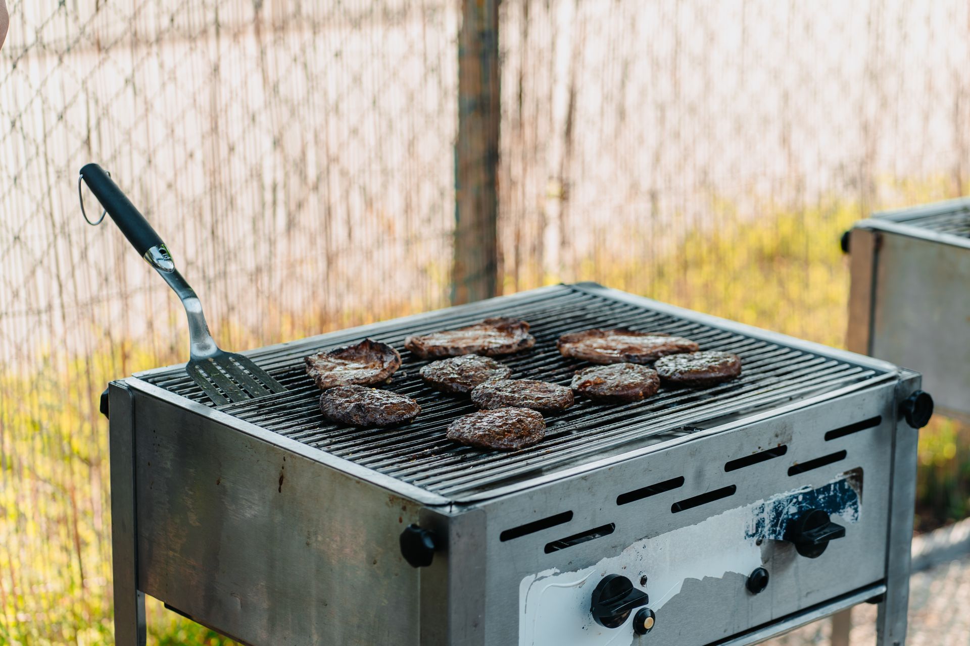 Hamburgers worden met een spatel op een grill bereid.