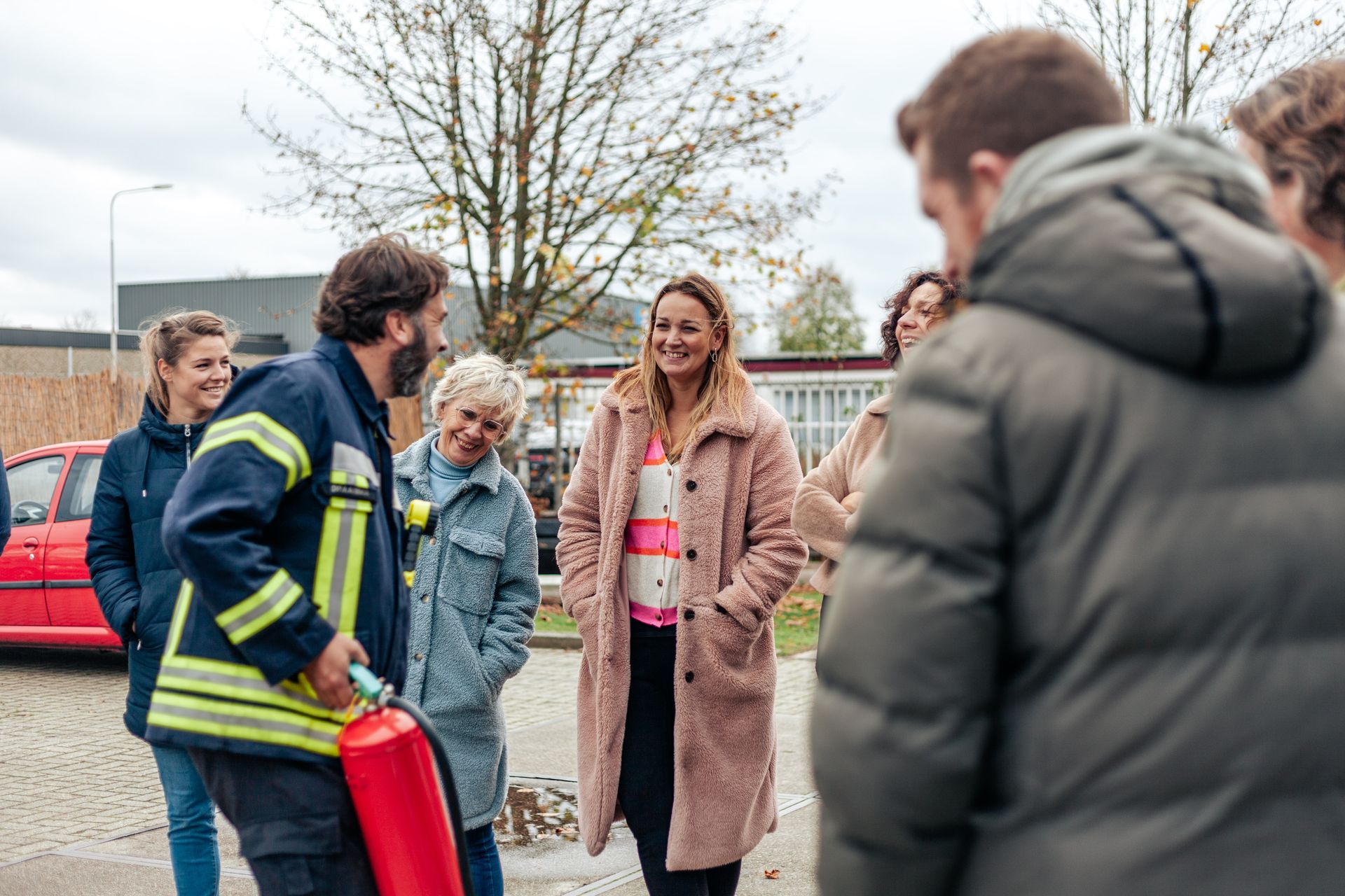 Een groep mensen staat rond een brandweerman die een brandblusser vasthoudt.