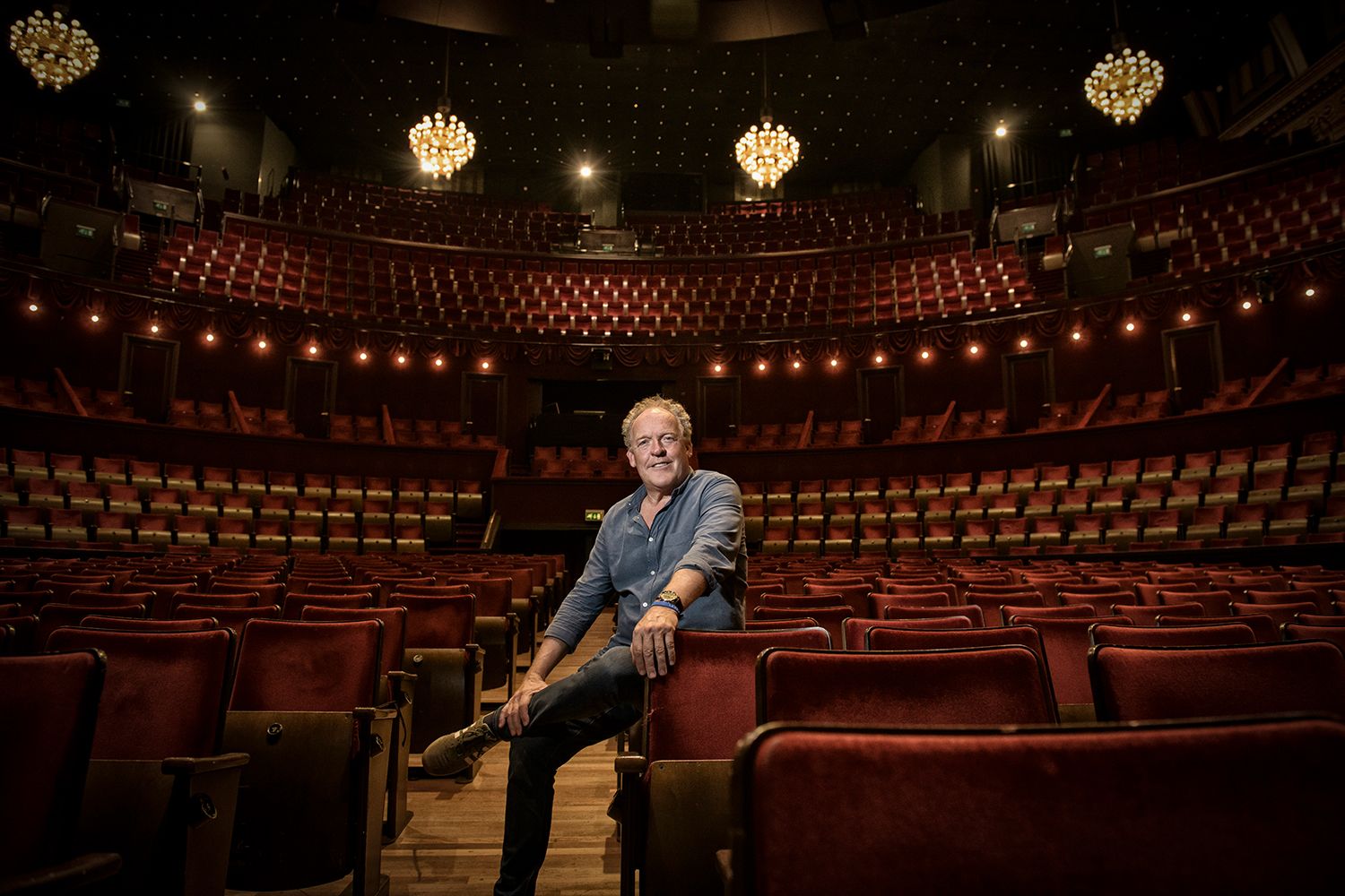 In een leeg theater zit een man op een stoel.