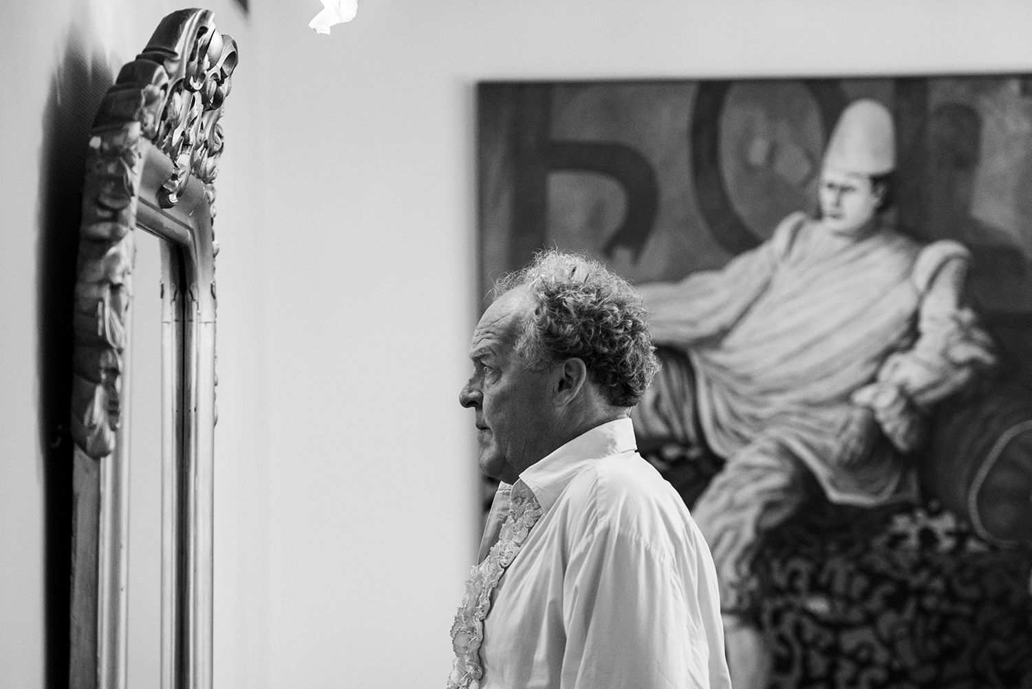 Een man kijkt naar een schilderij op een zwart-witfoto.