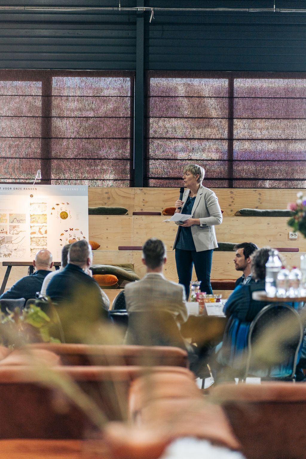 Een vrouw geeft een presentatie voor een groep mensen die op stoelen zitten.