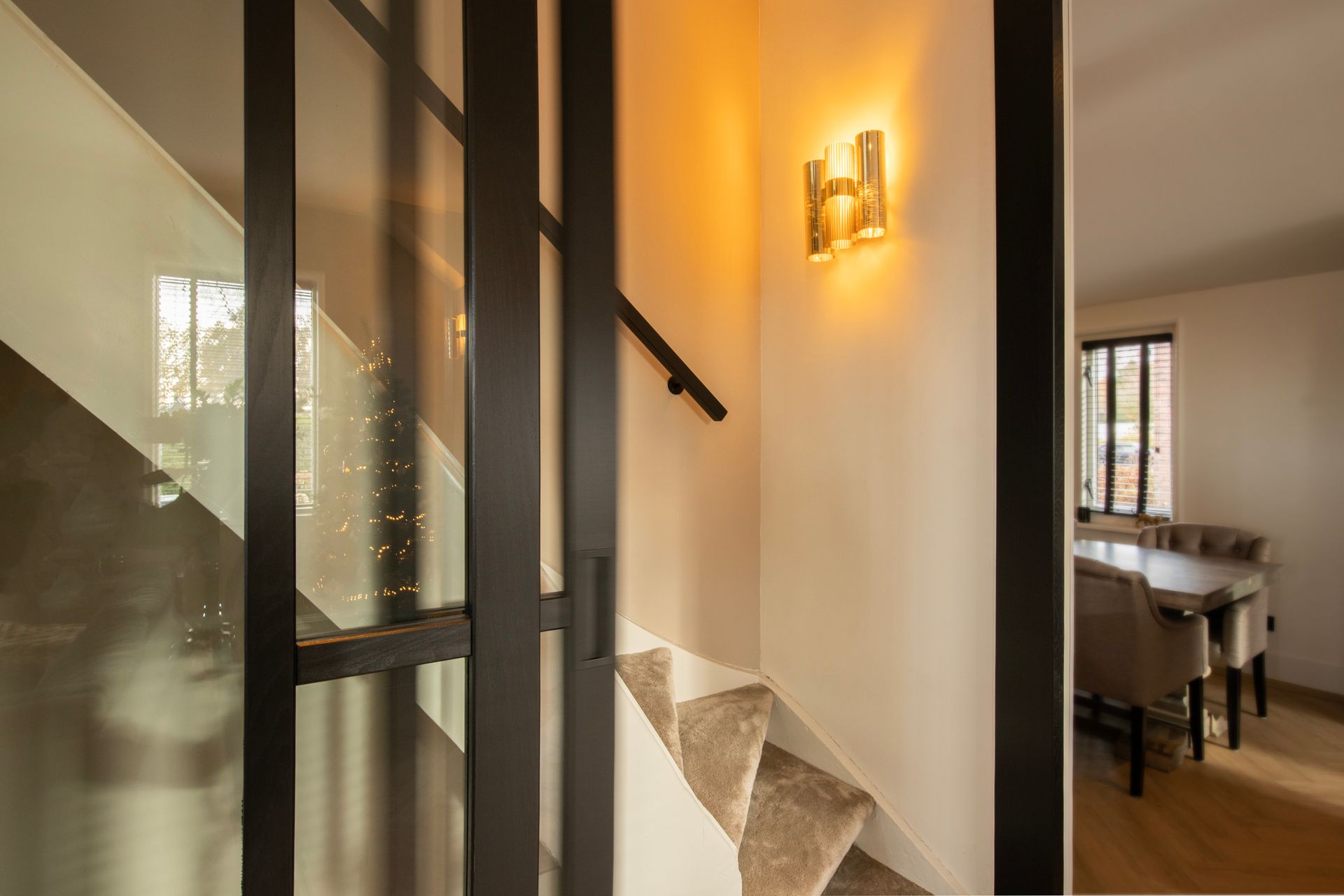 Een trap in een huis met een glazen wand en een lamp aan de muur.