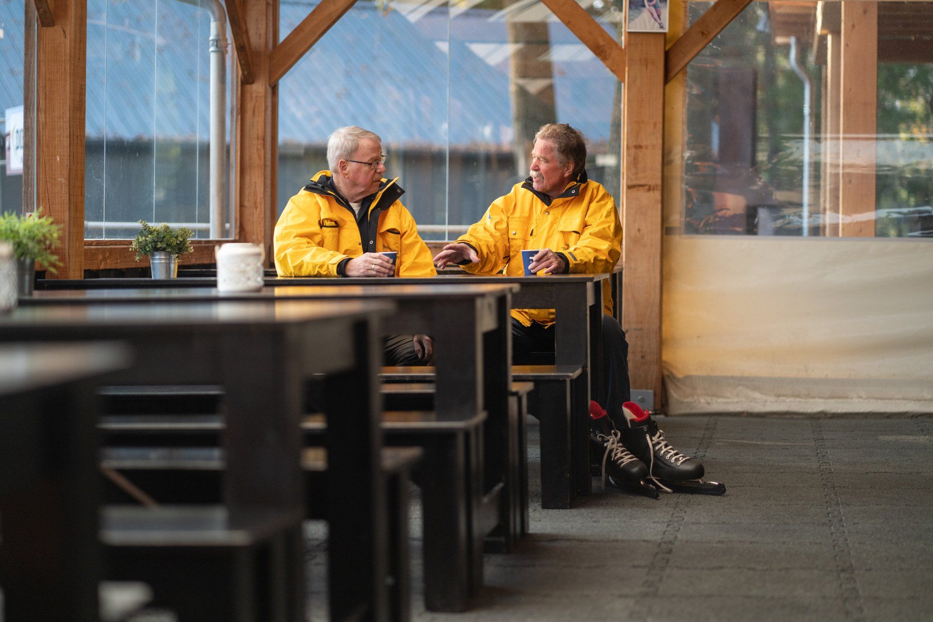 In een restaurant zitten twee mannen aan tafels met elkaar te praten.