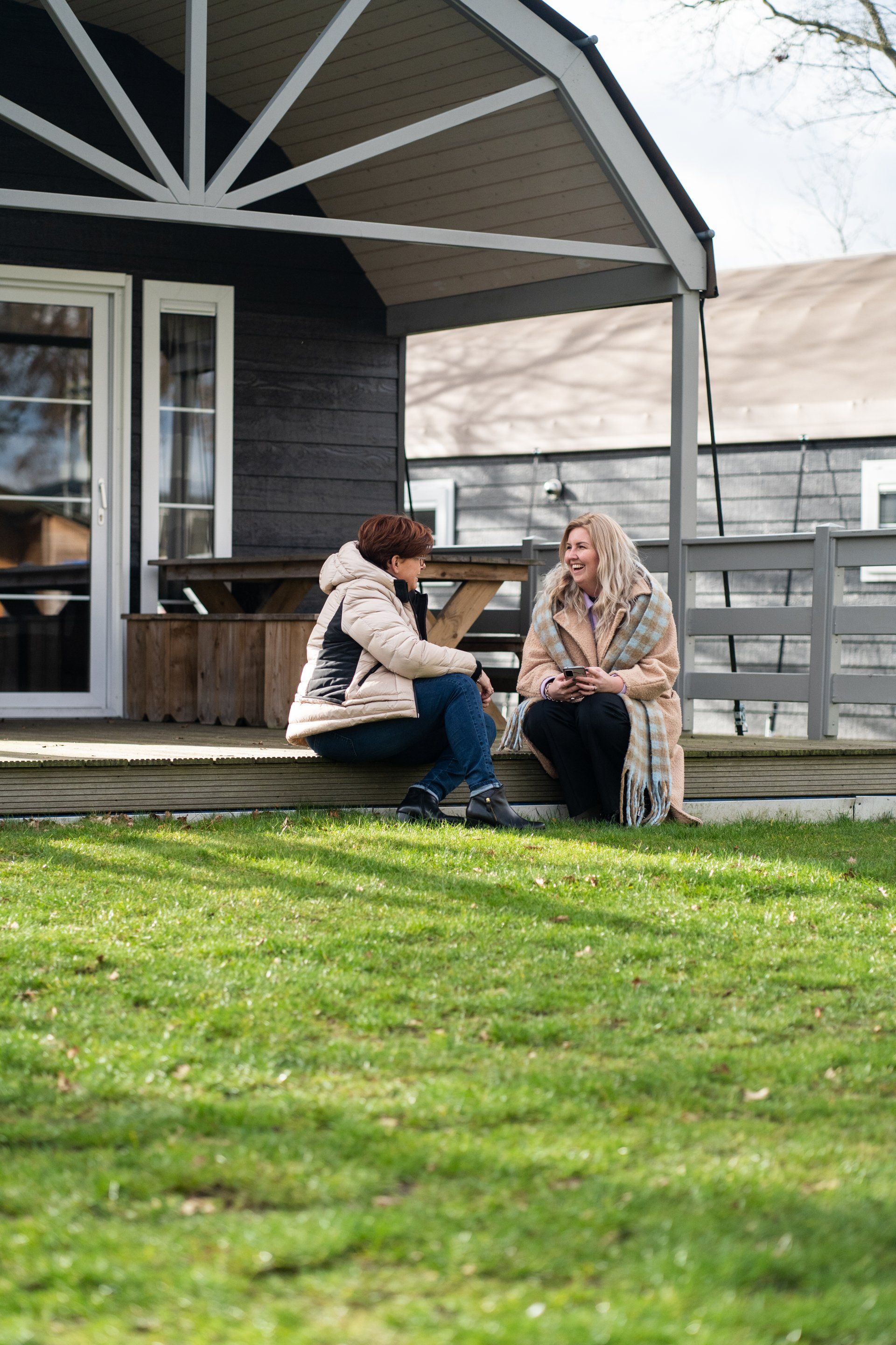 Twee vrouwen zitten op een terras voor een huis.