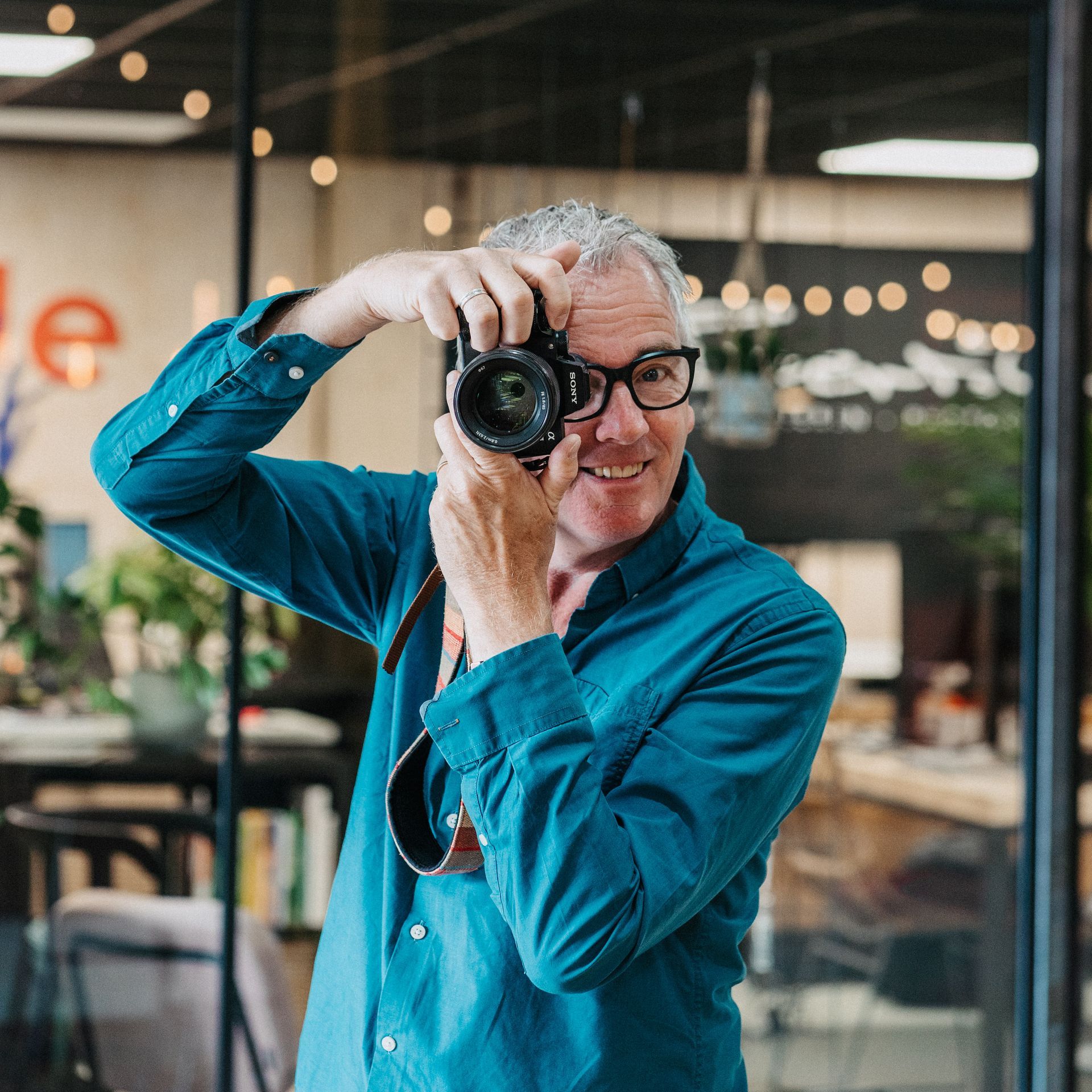 Een man in een blauw shirt maakt een foto met een camera.