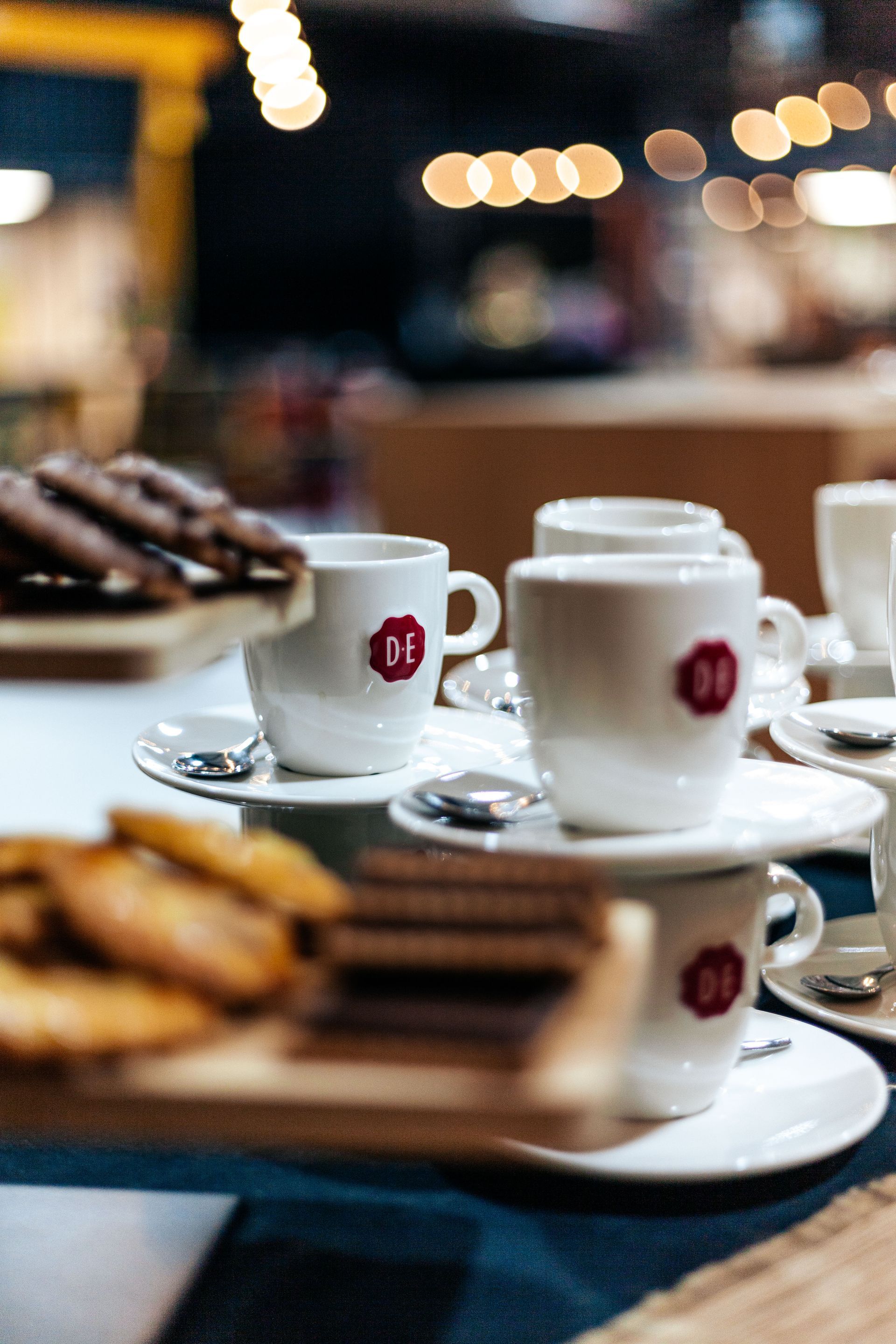 Een rij koffiekopjes en schotels op een tafel.