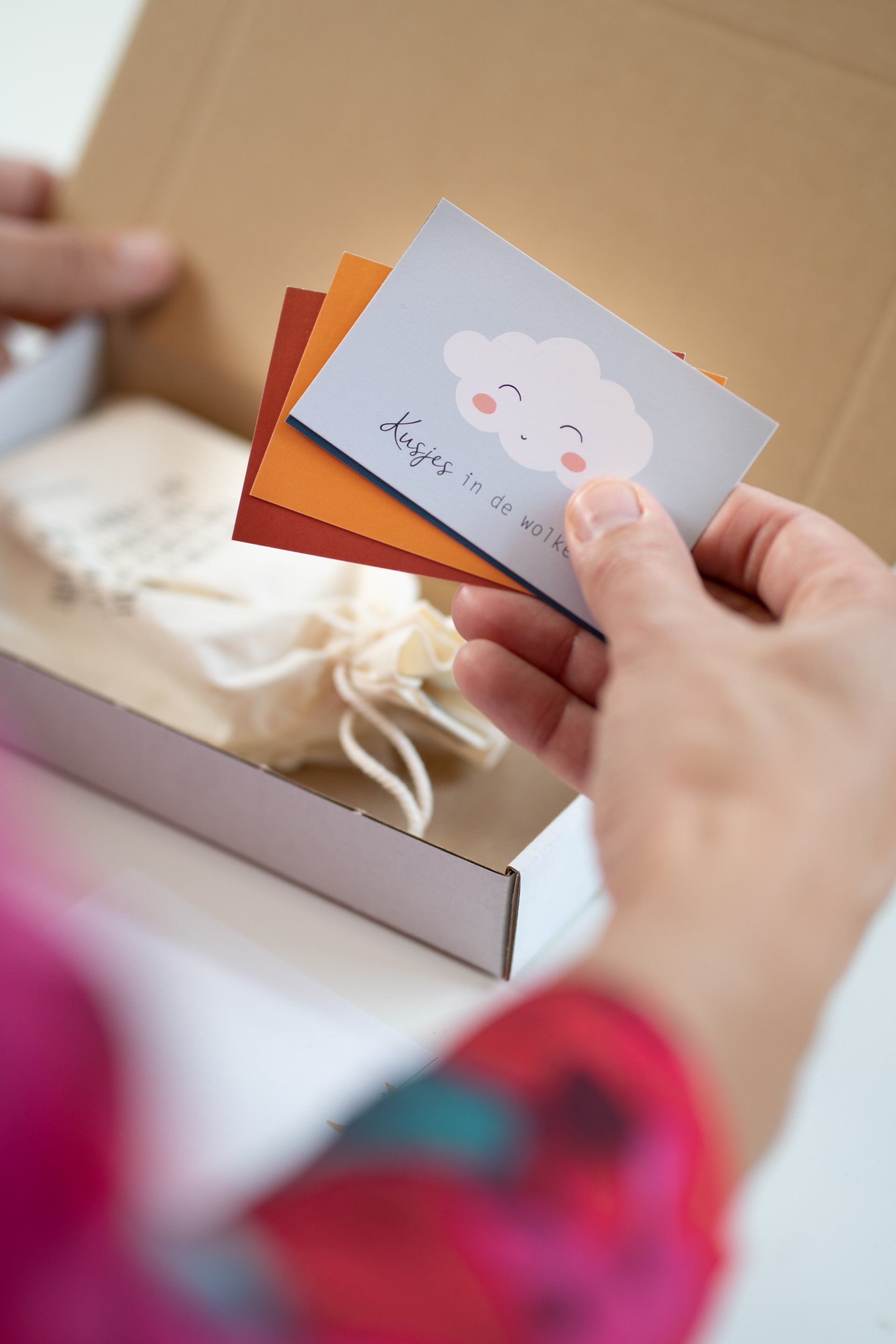 Een persoon houdt een kaart met een wolk erop voor een doos.