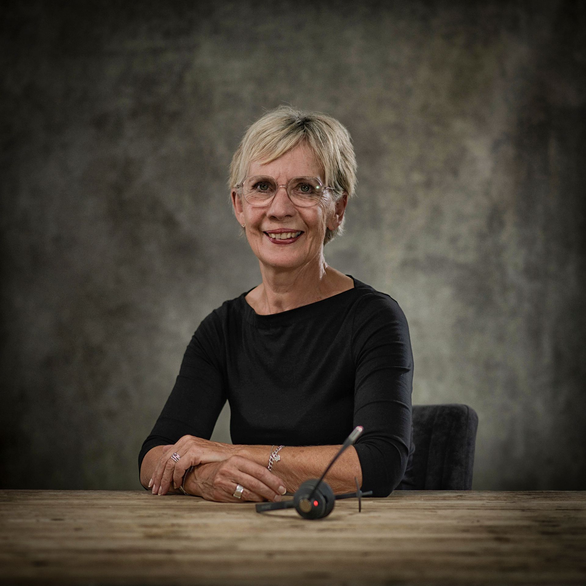 Een vrouw zit aan een tafel met een koptelefoon op.