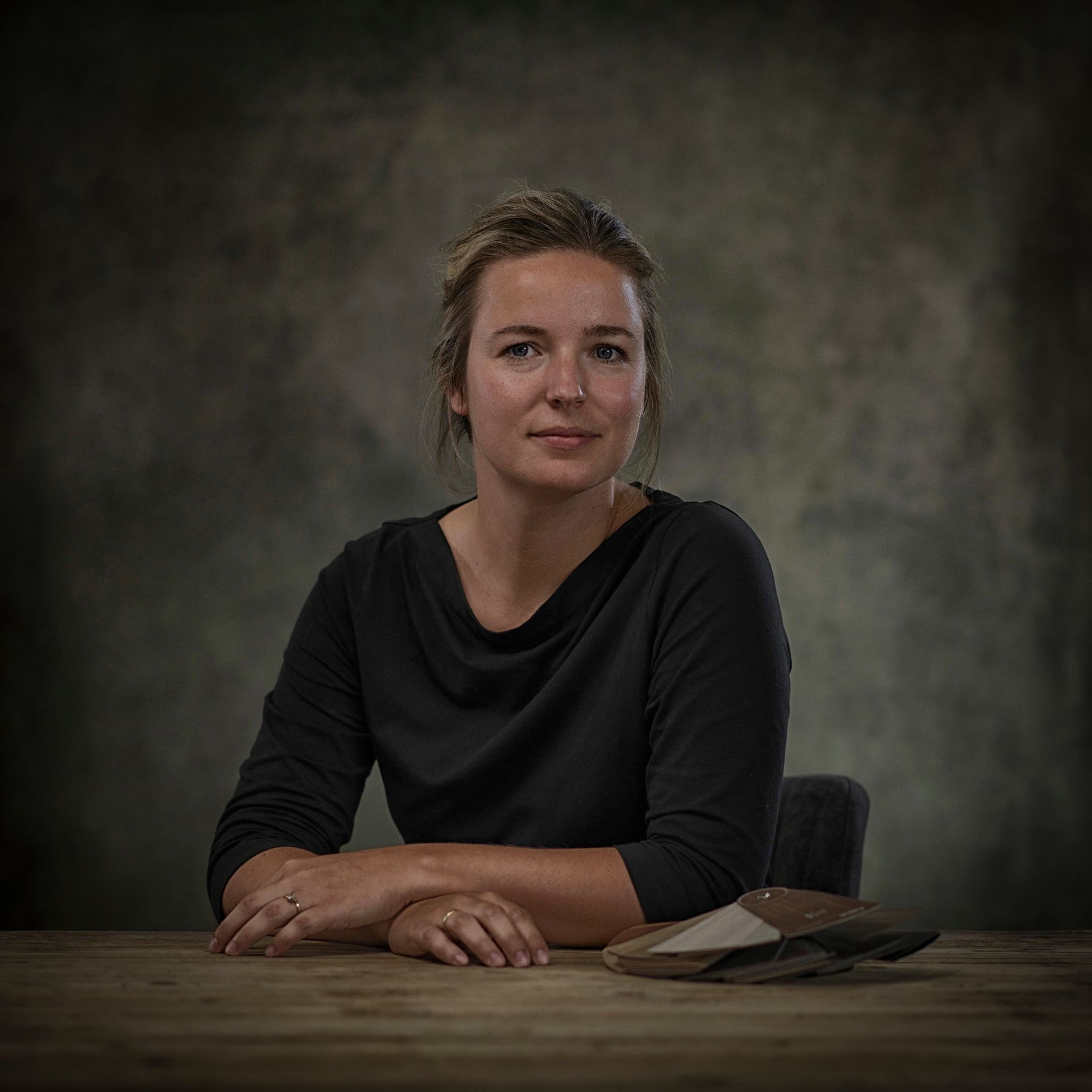 Een vrouw zit aan een tafel met haar handen op haar knieƫn.
