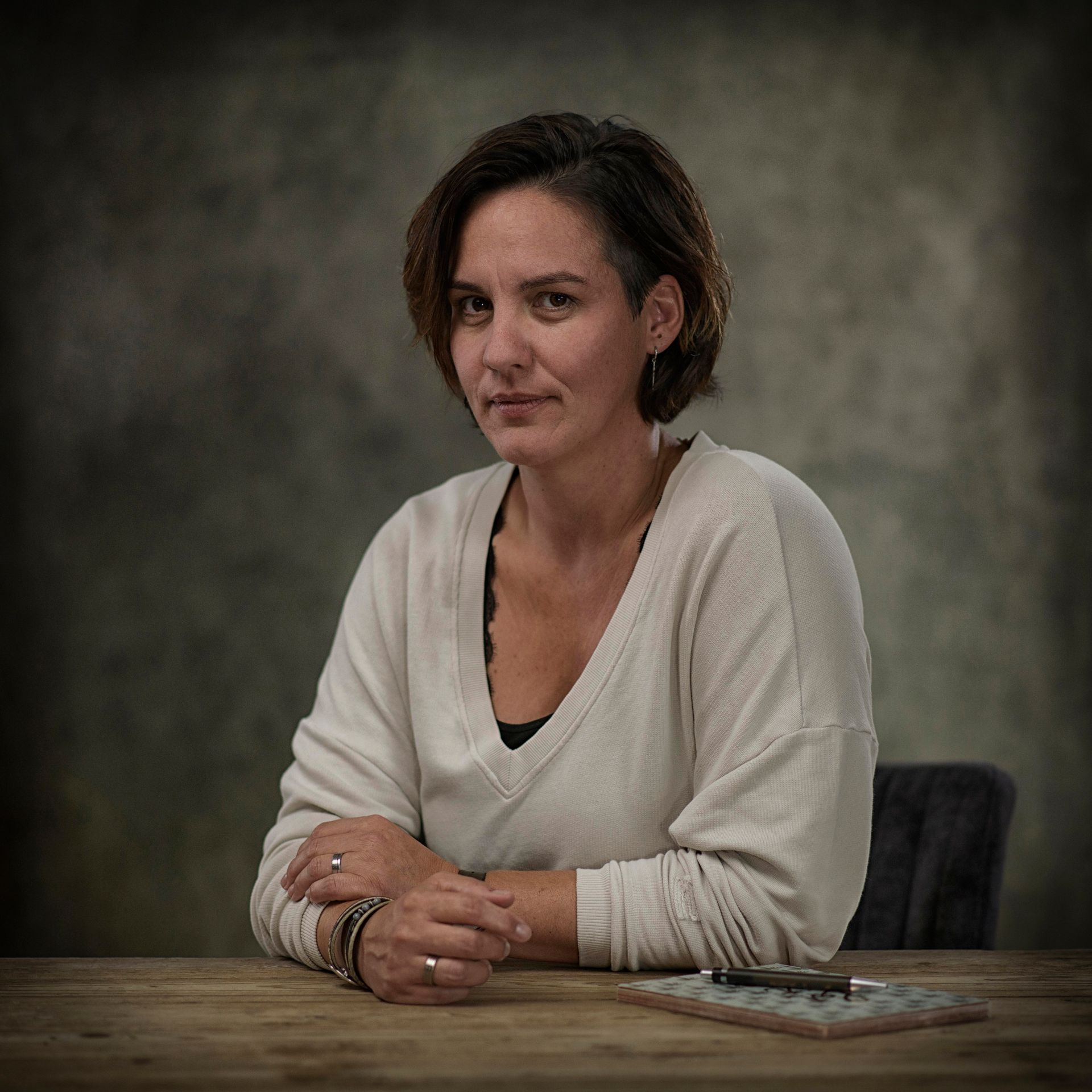 Jorinde zit aan een tafel met haar handen gevouwen.