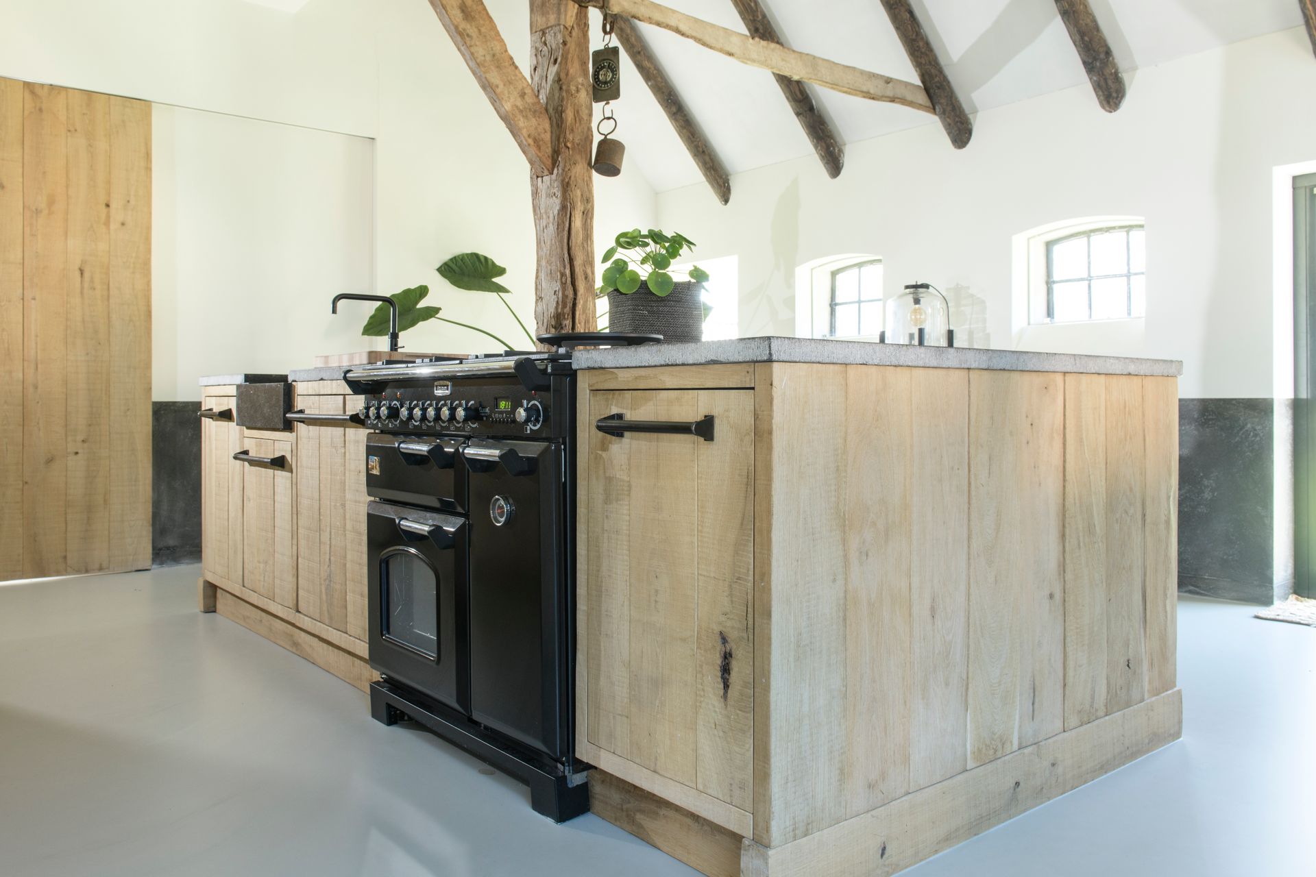 Een keuken met houten kasten en een zwart fornuis.