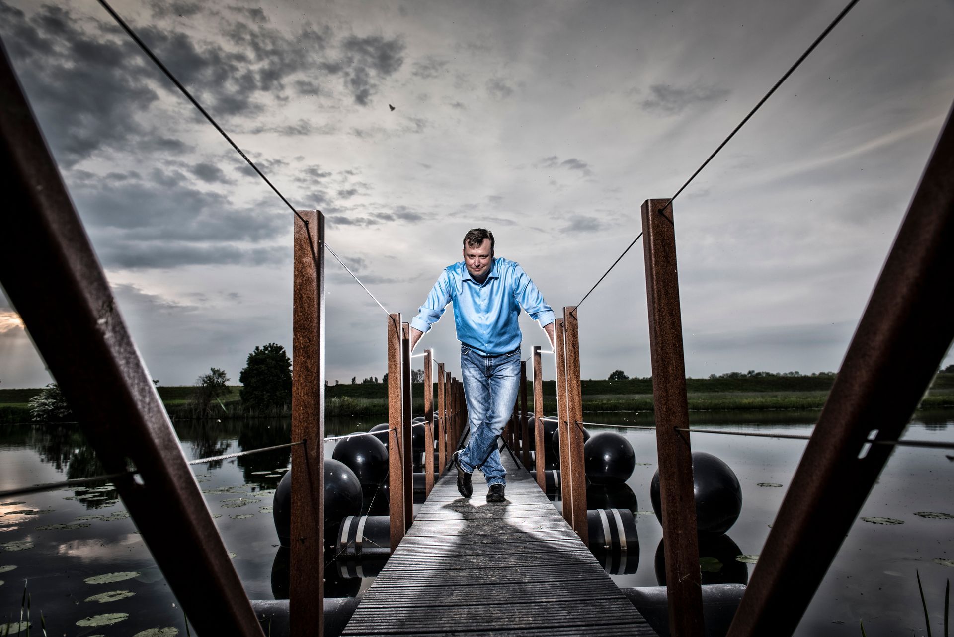 Een man loopt over een houten brug over een watermassa.