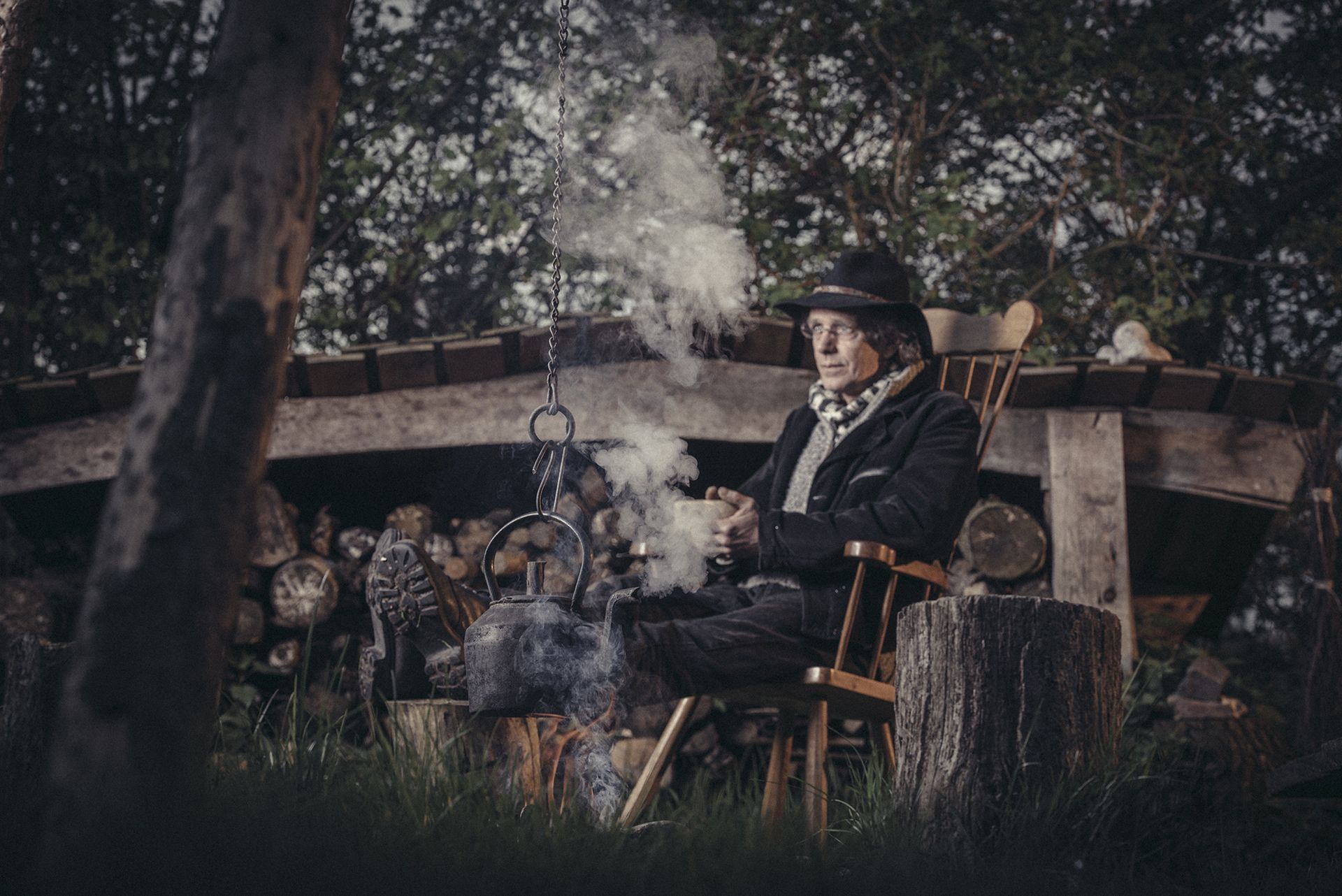 Een man zit in een stoel en er komt rook uit zijn mond.