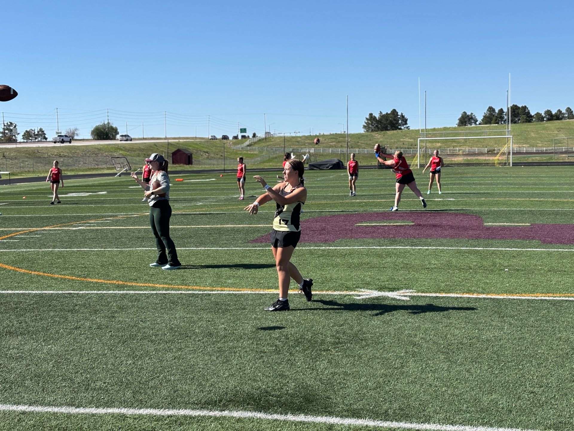 People playing on a sports field during a game, with players in red jerseys and a green turf background.