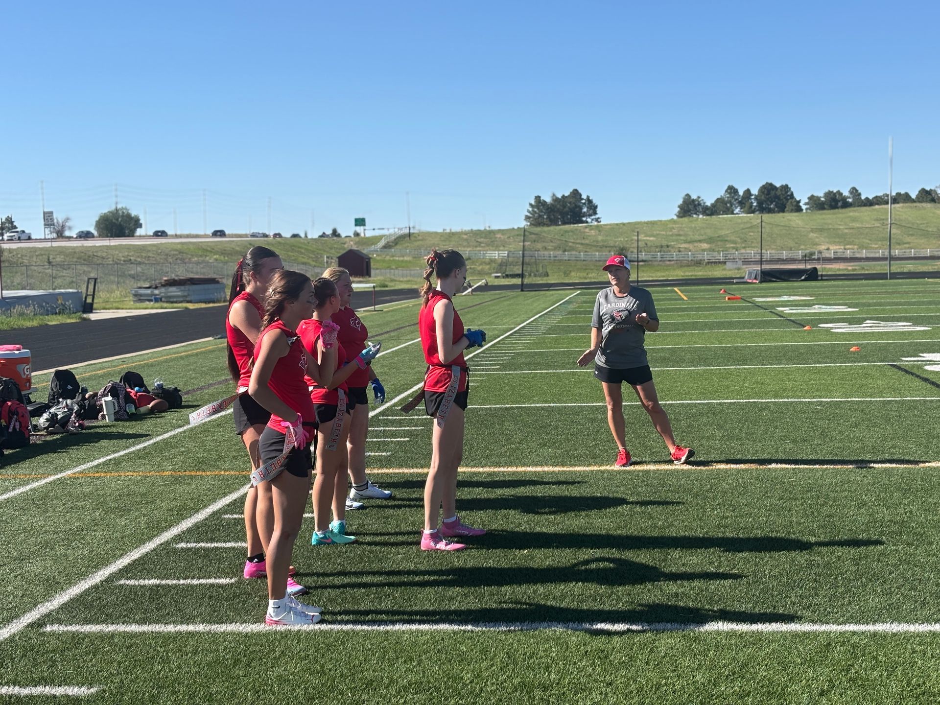 Girls in red sports uniforms standing on a football field during practice